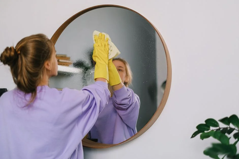 services-01 An adult male cleaning a glass window indoors, focusing on household chores and cleanliness.
